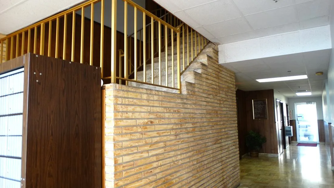 Floranada lobby staircase before renovation, with brick and dated wood railing